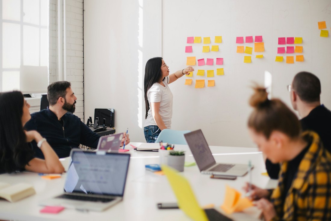 A small team comparing notes on a wall of sticky notes